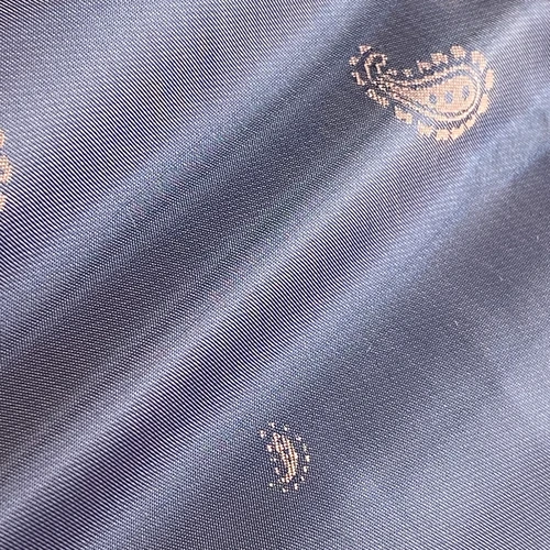 Dark fabric with gold paisley design, showcasing a luxurious texture perfect for stylish fashion and interior decor.
