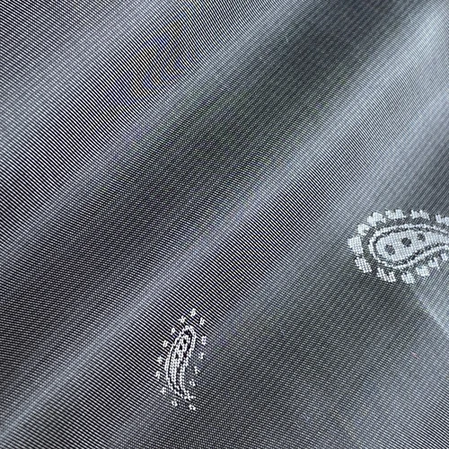 Close-up of black polka dot fabric with delicate embroidery patterns, showcasing texture and intricate design.