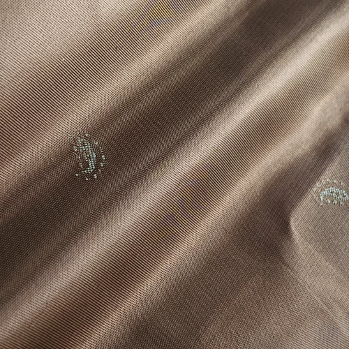 Brown fabric texture with subtle paisley embroidery, showcasing intricate details and smooth surface.