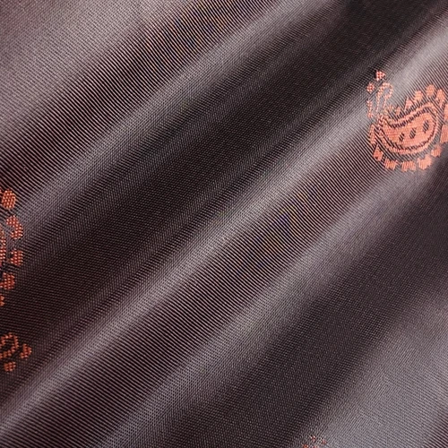 Elegant fabric with a subtle paisley pattern in brown and orange tones, featuring a smooth, lustrous texture.