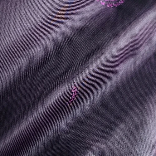 Close-up of elegant purple silk fabric with delicate embroidery details, showcasing its smooth texture and rich color.