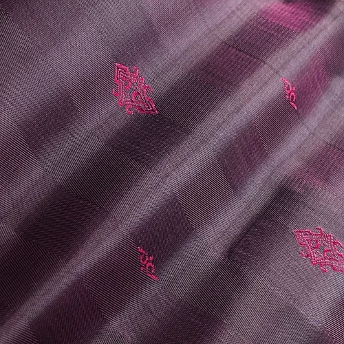 Close-up of a textured fabric in purple and pink hues with subtle geometric patterns.