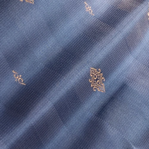 Blue patterned fabric with subtle gold logo designs, showcasing a sophisticated and elegant textile texture.