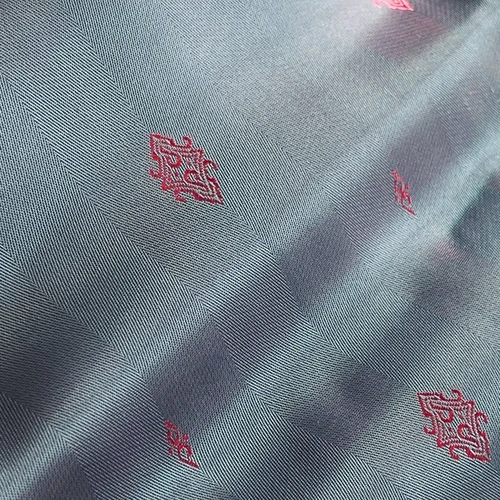 Silk fabric with red embroidered patterns on a diagonal design, showcasing an elegant and luxurious texture.
