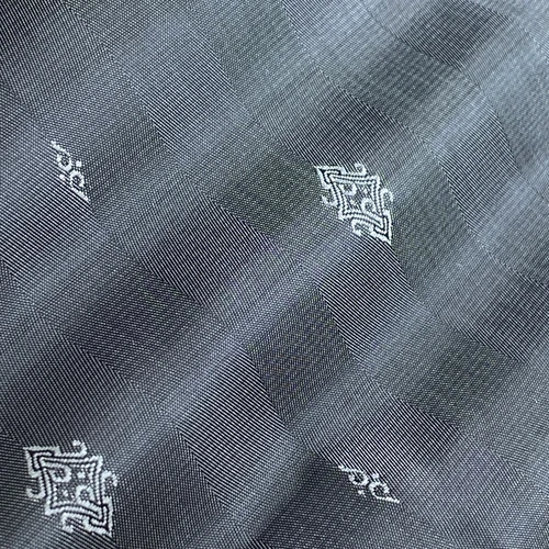 Elegant grey fabric texture with intricate white embroidered patterns, perfect for modern textile and fashion design.