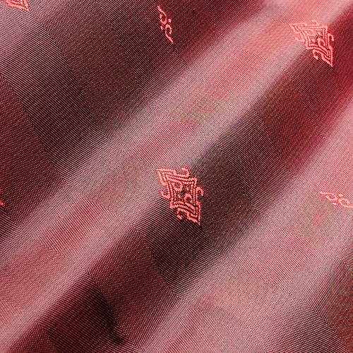 Close-up of a pink and black paisley fabric pattern with intricate designs, highlighting woven texture and details.