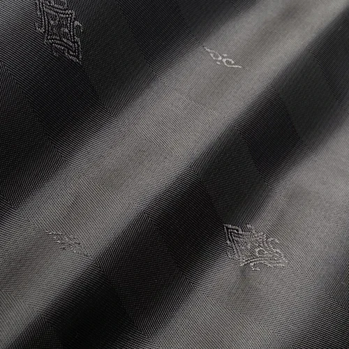 Close-up of textured gray fabric with subtle checkered pattern and decorative details.