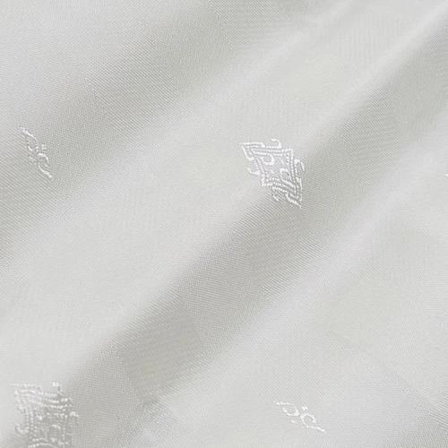 Close-up of elegant white fabric with subtle embroidered patterns, showcasing intricate textile design and texture.
