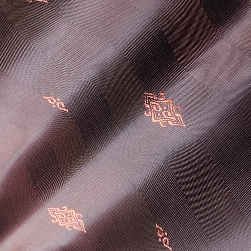Close-up of textured fabric with pink geometric patterns on a dark background, showcasing intricate design and detail.