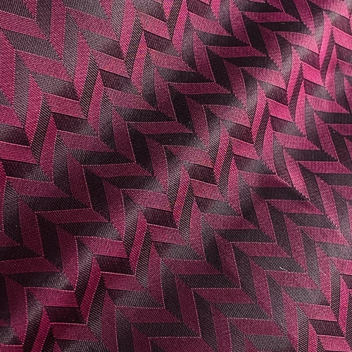 Close-up of textured burgundy fabric with a geometric zigzag pattern, creating an elegant and stylish design.