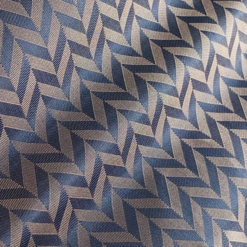 Close-up of blue and gray geometric patterned fabric with interlocking chevron design, showcasing texture and weave.