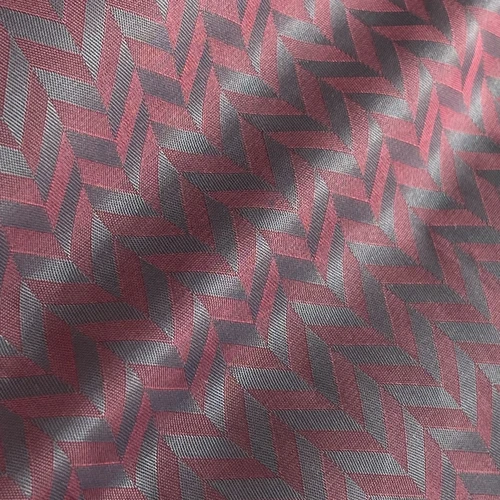 Close-up of red and gray chevron-patterned textile fabric in diagonal lighting.