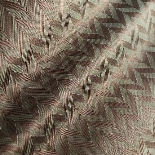 Herringbone pattern fabric in subtle brown and green tones illuminated by sunlight.