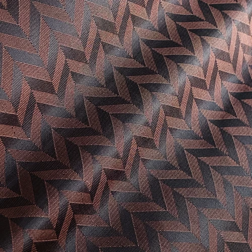 Brown and black zigzag patterned fabric with a textured surface, ideal for fashion or interior design.