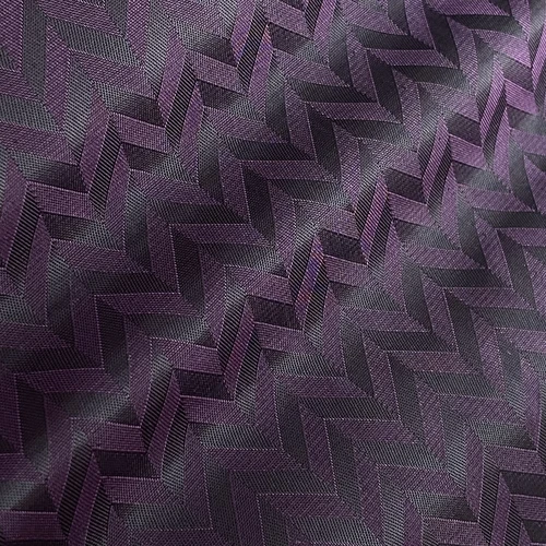 Purple textured fabric with a herringbone pattern, showcasing elegant design and intricate details in light and shadow.