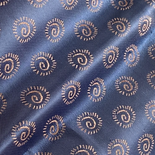 Blue fabric with elegant spiral patterns, featuring intricate white embroidery, offers a stylish and sophisticated texture.