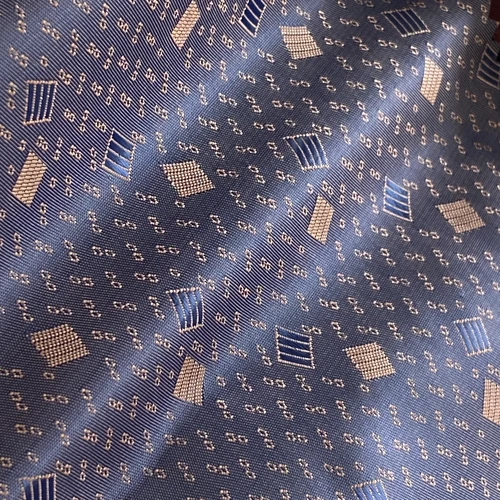Blue fabric with geometric pattern, featuring light blue and cream squares and rectangles. Textured, contemporary design.