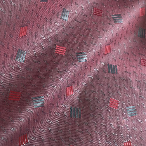 Maroon fabric with red and gray rectangular pattern, displaying unique texture and design for fashion or interior use.