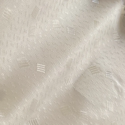 Creamy white fabric with intricate embossed patterns, showcasing elegant texture and subtle geometric designs.