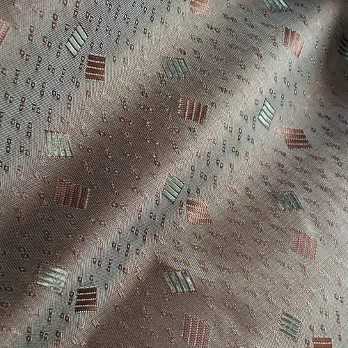 Textured fabric with geometric square patterns in neutral tones, featuring subtle stripes and dots.