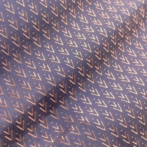 Close-up of a purple fabric with a diagonal arrow pattern in metallic shades. Perfect for fashion or interior design context.
