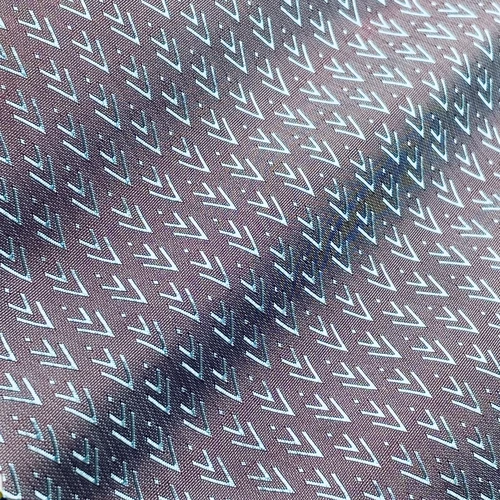 Close-up of fabric with repeating arrow patterns in blue and white on a brown background.