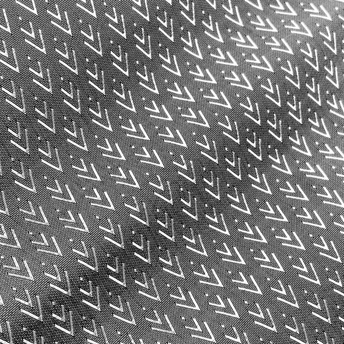 Monochrome geometric pattern of repeating V-shapes on textured surface.