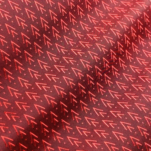 Close-up of a red fabric with repeated arrow patterns, showcasing intricate textile design and vibrant color.