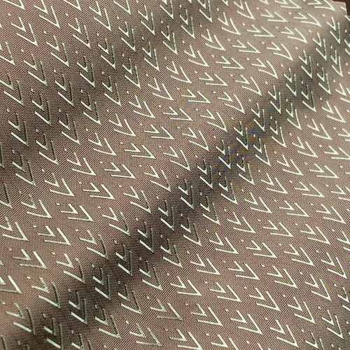 Close-up of brown fabric with silver chevron pattern, textured design in focus.