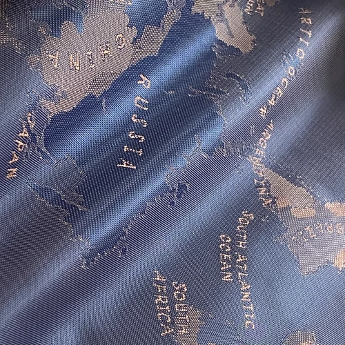 Close-up of a blue fabric with an embroidered world map showing continents and oceans.