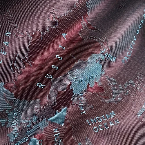Close-up of a textured map pattern featuring Russia, China, Japan, and the Pacific Ocean on a maroon fabric.