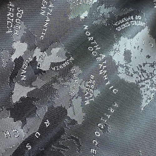Textured fabric map displaying continents and oceans in grayscale, including the North Atlantic Ocean and South America.