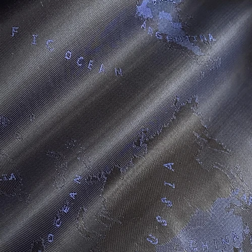 Close-up of a dark fabric with an embossed world map design, highlighting continents and oceans in blue and gray tones.