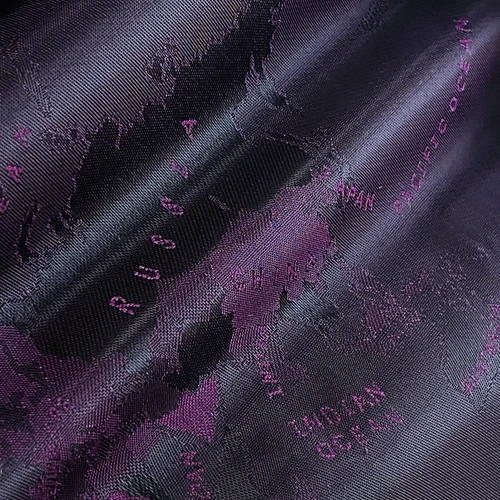 Close-up fabric texture with a dark world map pattern, highlighting countries like Russia and China in purple shades.