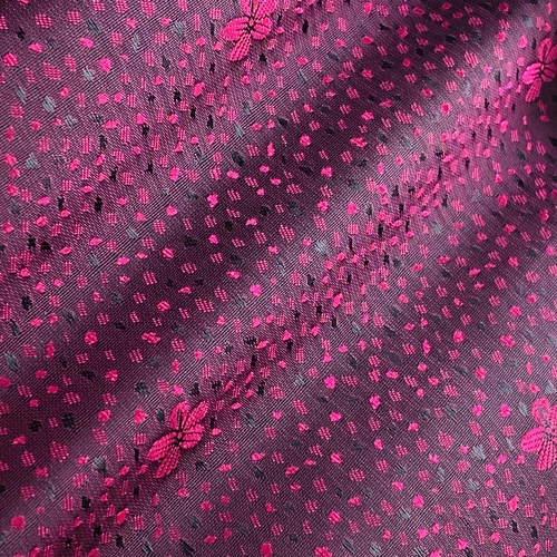 Pink floral patterned fabric with intricate stitching and dotted design on a dark background.