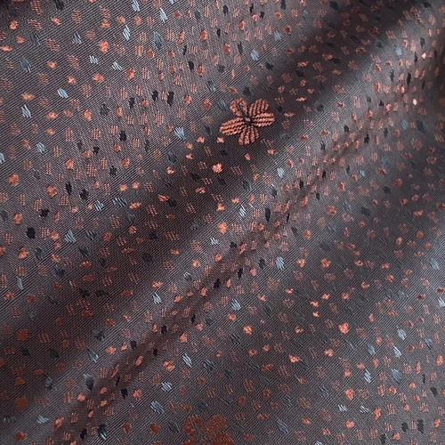 Close-up of dark fabric with orange and blue floral patterns, folded texture.