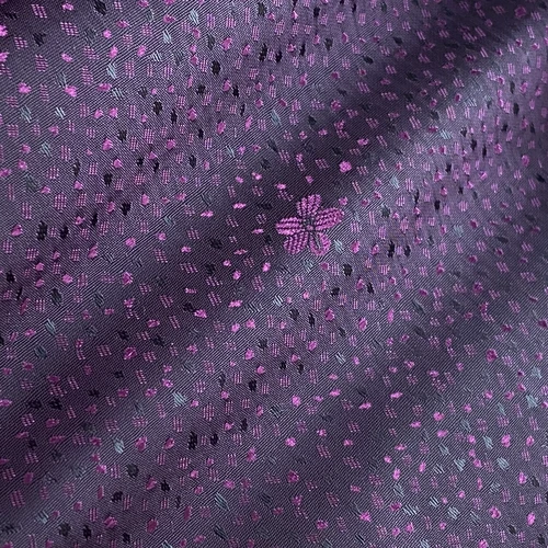 Purple fabric with intricate floral embroidery and fine patterns, featuring a small flower design in the center.
