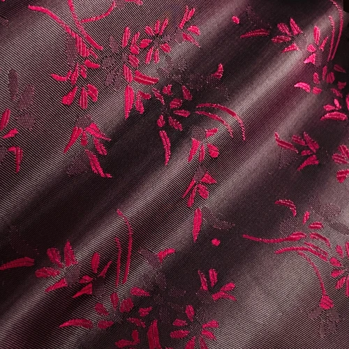 Elegant red floral embroidery on dark fabric, showcasing intricate design and texture for fashion or home decor.