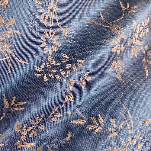 Blue fabric with gold floral embroidery, showcasing intricate designs and elegant patterns.