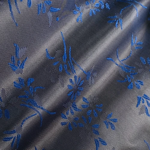Close-up of elegant blue floral jacquard fabric with a shiny texture and intricate pattern.