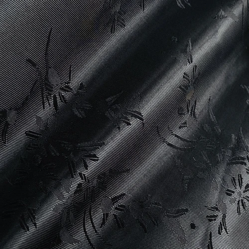 Close-up of black fabric with floral patterns, showcasing detailed texture and design.