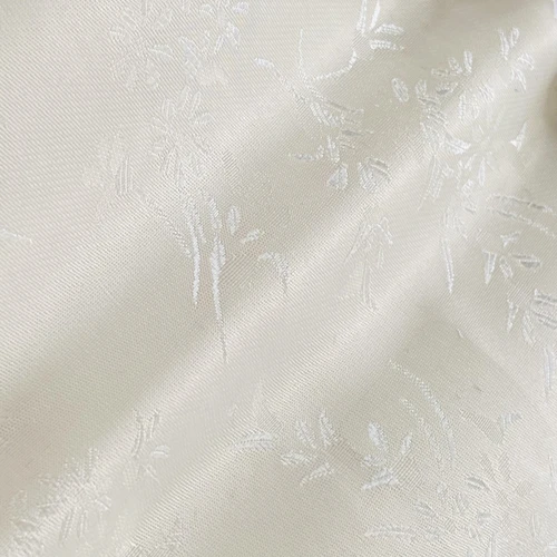 Close-up of white floral-patterned fabric with subtle texture and elegant design.
