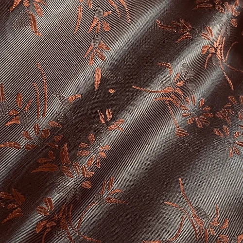 Close-up of elegant brown floral embroidery on a textured fabric, showcasing intricate details and luxurious design.