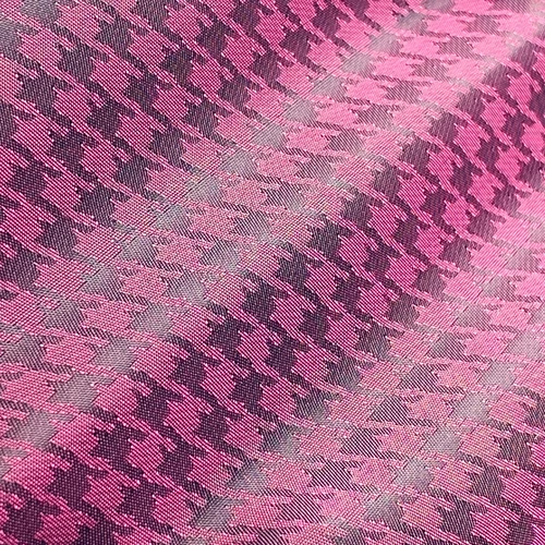 Pink and gray houndstooth fabric with a textured, overlapping pattern design in close-up view.