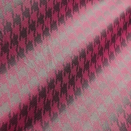 Pink and gray houndstooth fabric pattern close-up, displaying textured diagonal zigzag design.