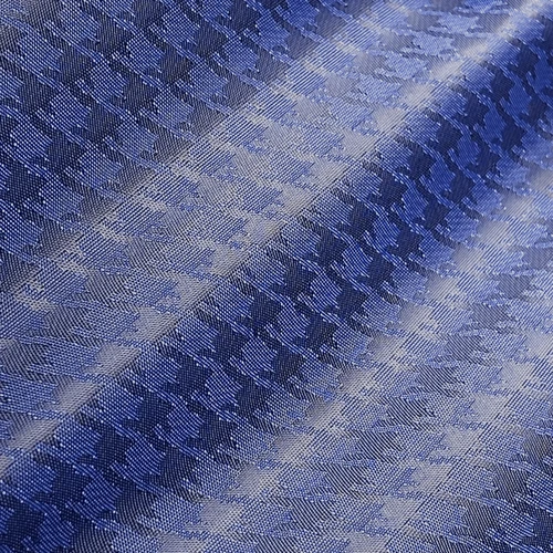 Close-up of blue woven fabric with a textured houndstooth pattern, showcasing detailed craftsmanship and elegant design.