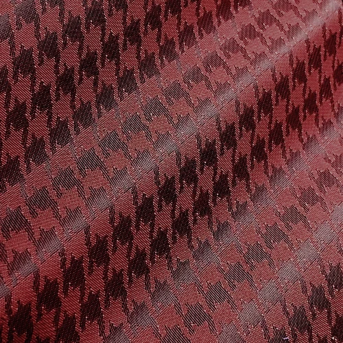 Close-up of red and black houndstooth fabric, showcasing its classic checkered pattern texture.
