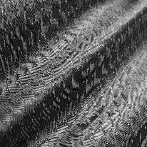 Close-up of black and white houndstooth patterned fabric with light and shadow detail.