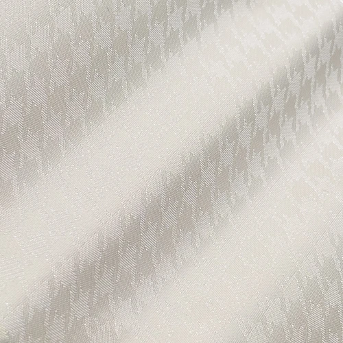 Close-up of a textured white fabric with a subtle houndstooth pattern, highlighting its intricate design and smooth surface.