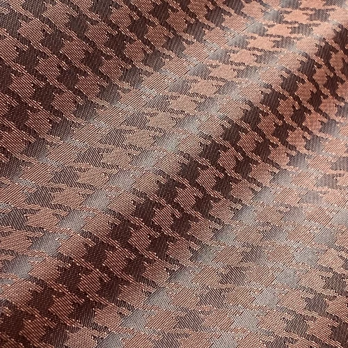 Close-up of a brown houndstooth fabric with a textured pattern, showcasing intricate weaving and elegant design.